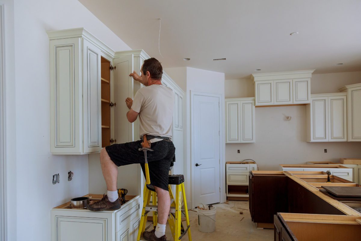 Man installing or repairing kitchen cabinets using tools.