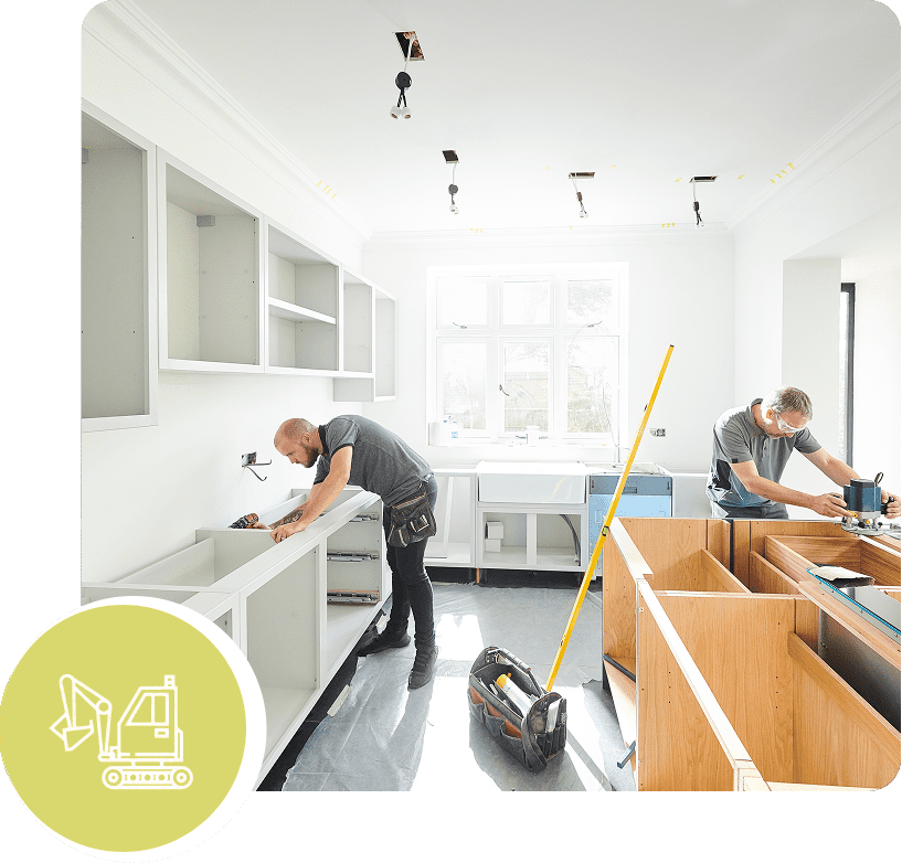 Two workers installing kitchen cabinets in a bright, modern space.